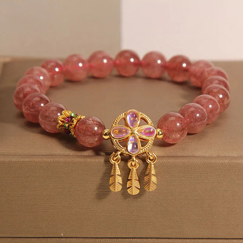 Women's strawberry quartz crystal bracelet with a four-leaf clover dream catcher ball pendant.