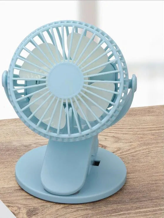 Small white clip fan with plastic blades attached to a surface, showing USB cable and piano button switch.