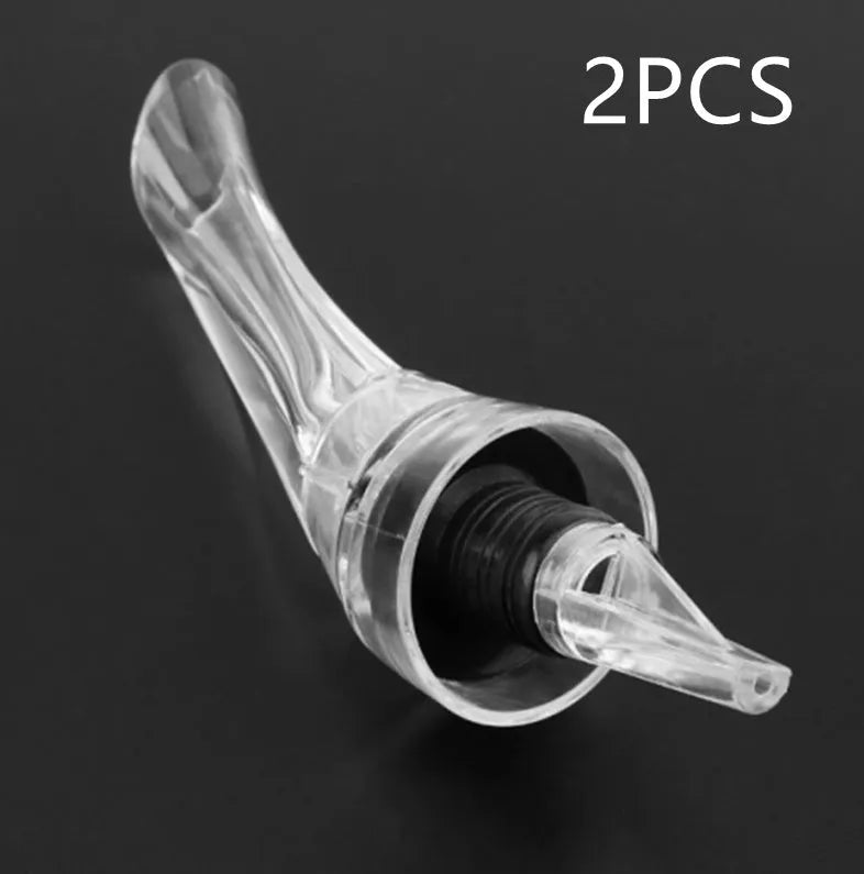 A slender, clear acrylic wine aerator pourer with a stainless steel filter inside, shown next to a wine glass.