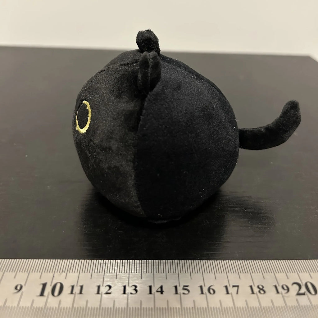 Black fluffy cat plush toy with printed face, sitting upright as a soft cushion.