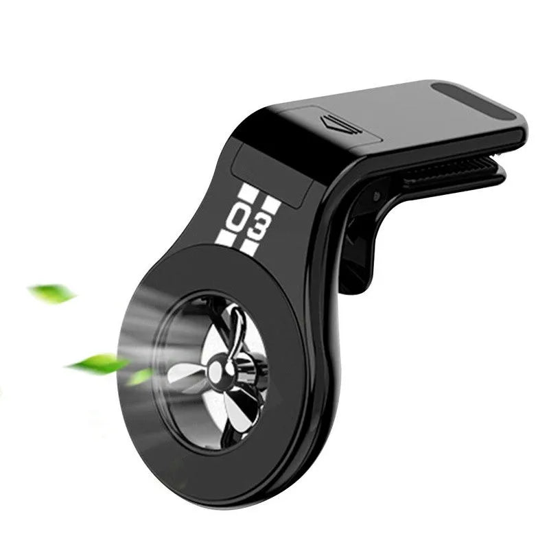 Black magnetic car phone holder clipped to a car air vent, showing adjustable paddle and fragrant slice.