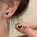 Three pairs of women's heart-shaped alloy earrings in gold, black, white, and pink colours