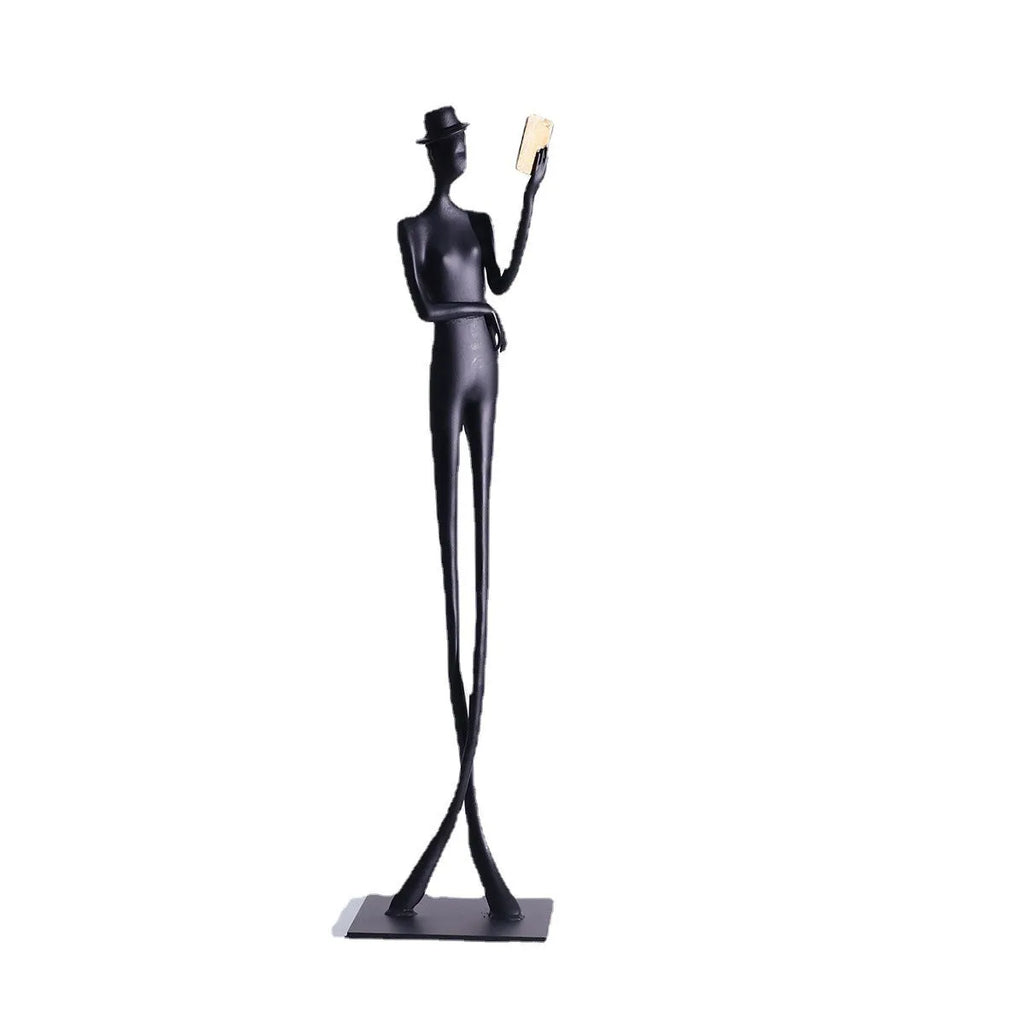 Black metal sculpture of a seated woman reading a book, modern minimalist desk decor.