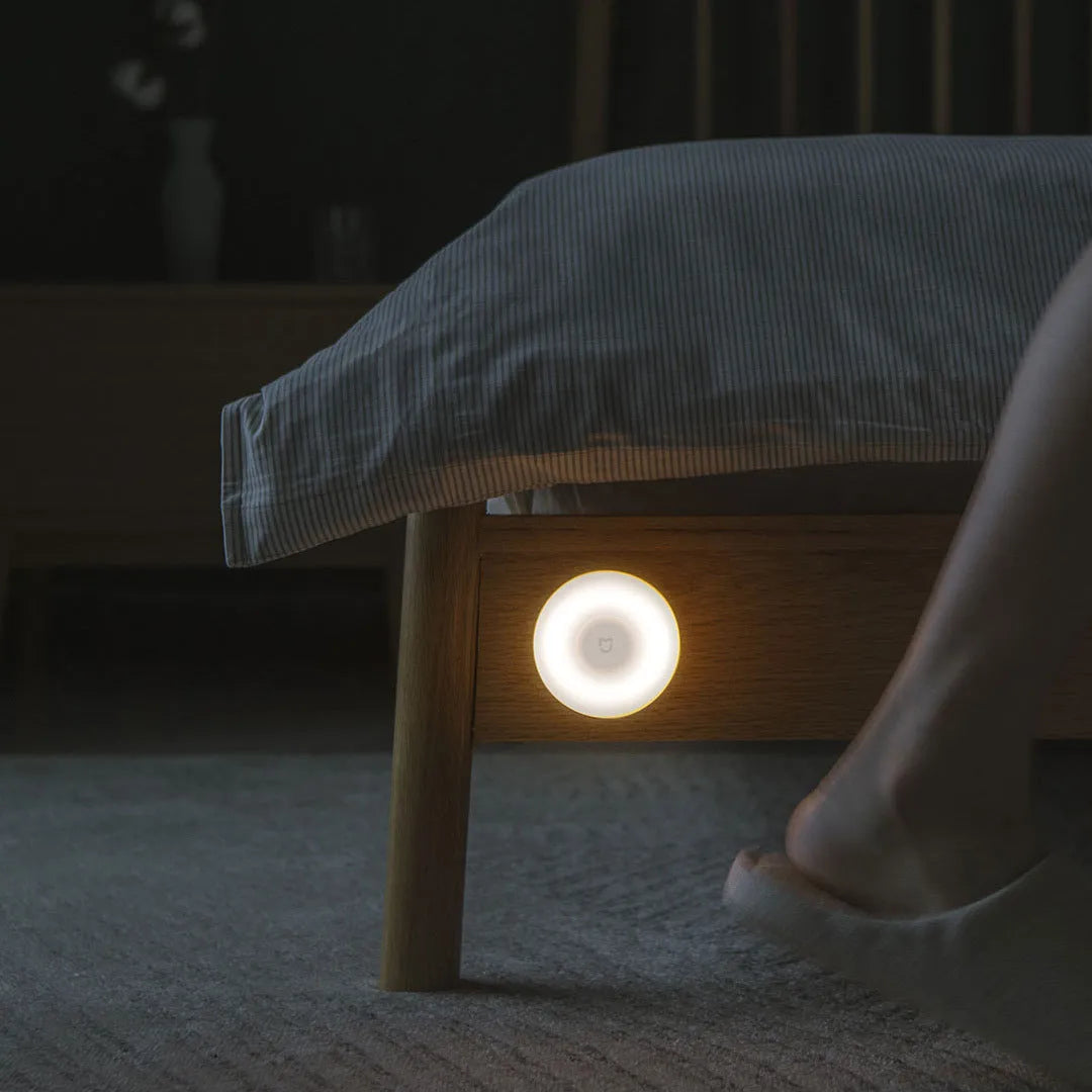 White modern bedside table lamp with human body induction and Bluetooth on a nightstand.