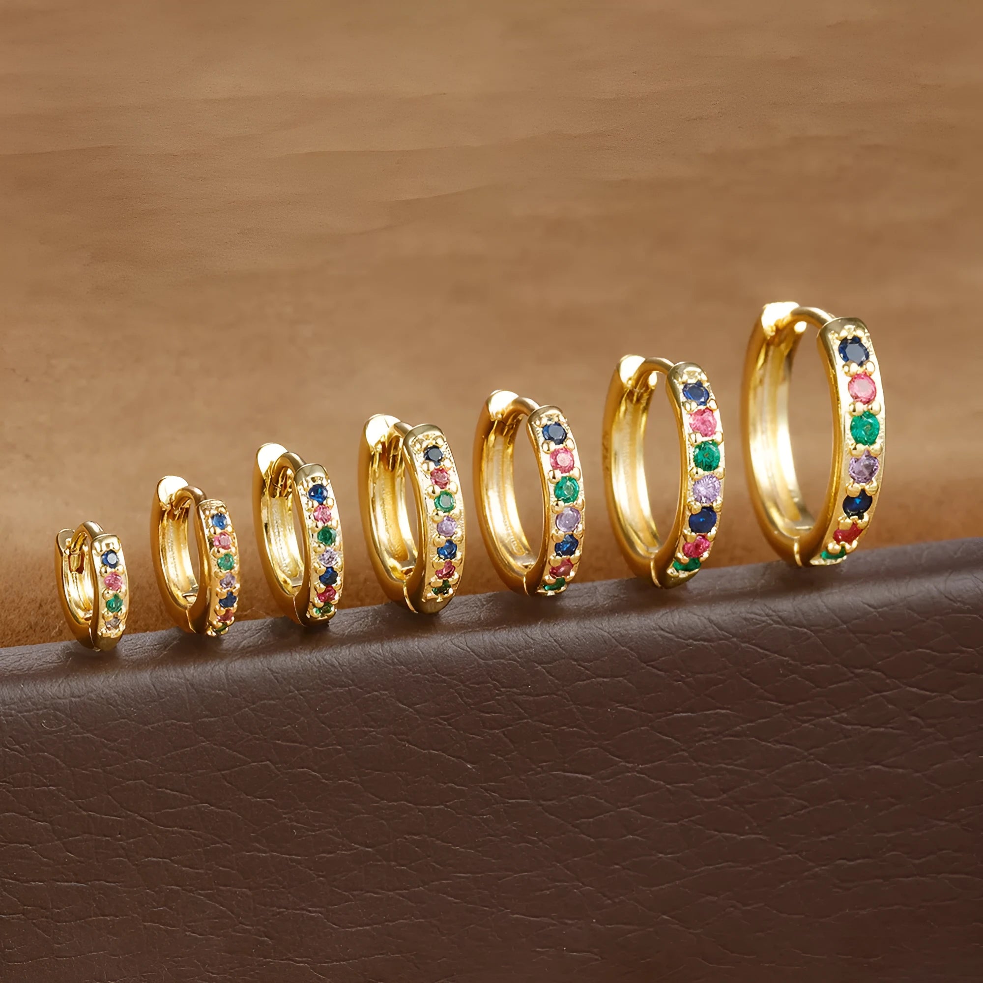 Set of gold, rose gold, and silver perforated circle stud earrings in multiple sizes on a flat surface.