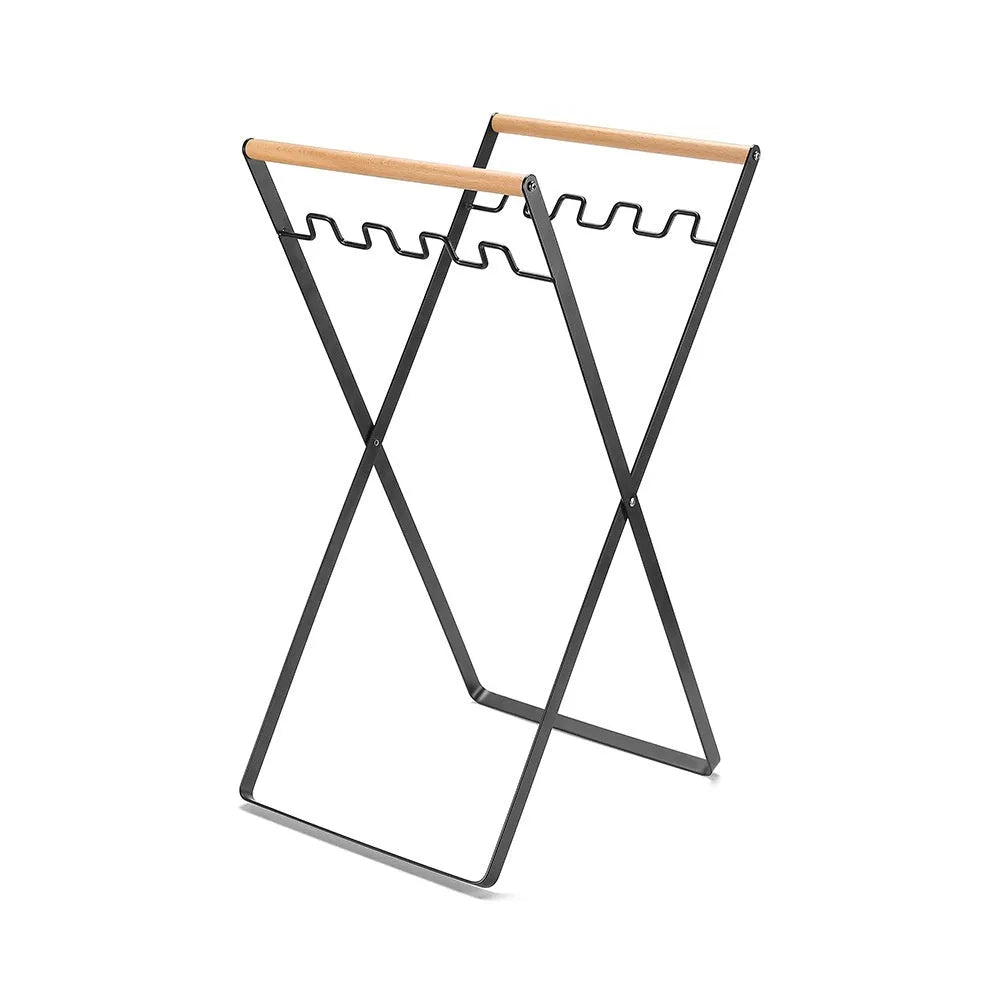 Black iron folding trash storage rack with wooden handle mounted on a wall.