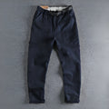 Men's khaki cotton work trousers with a black buckle belt and zip fly closure.