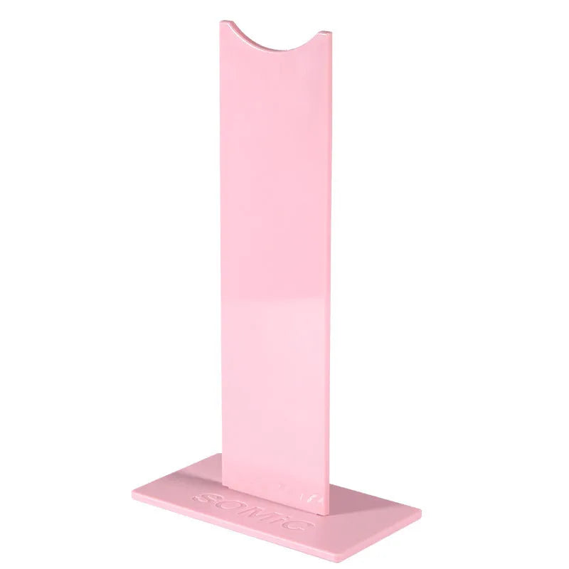 Pink and black detachable head-mounted headphone stand on a desk with a non-slip silicone base.
