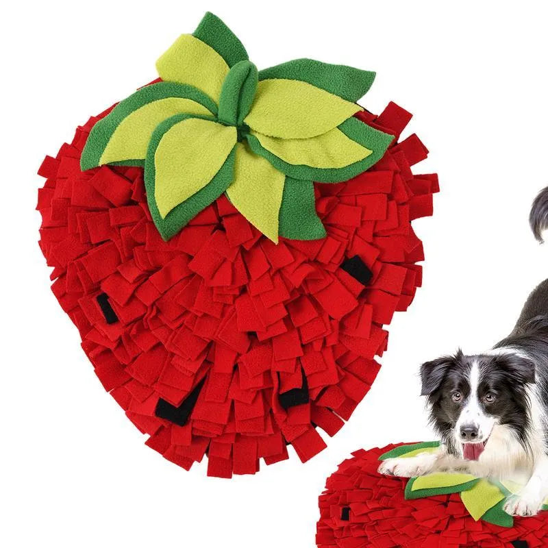 Red and green strawberry-shaped snuffle mat for dogs and cats on a floor.