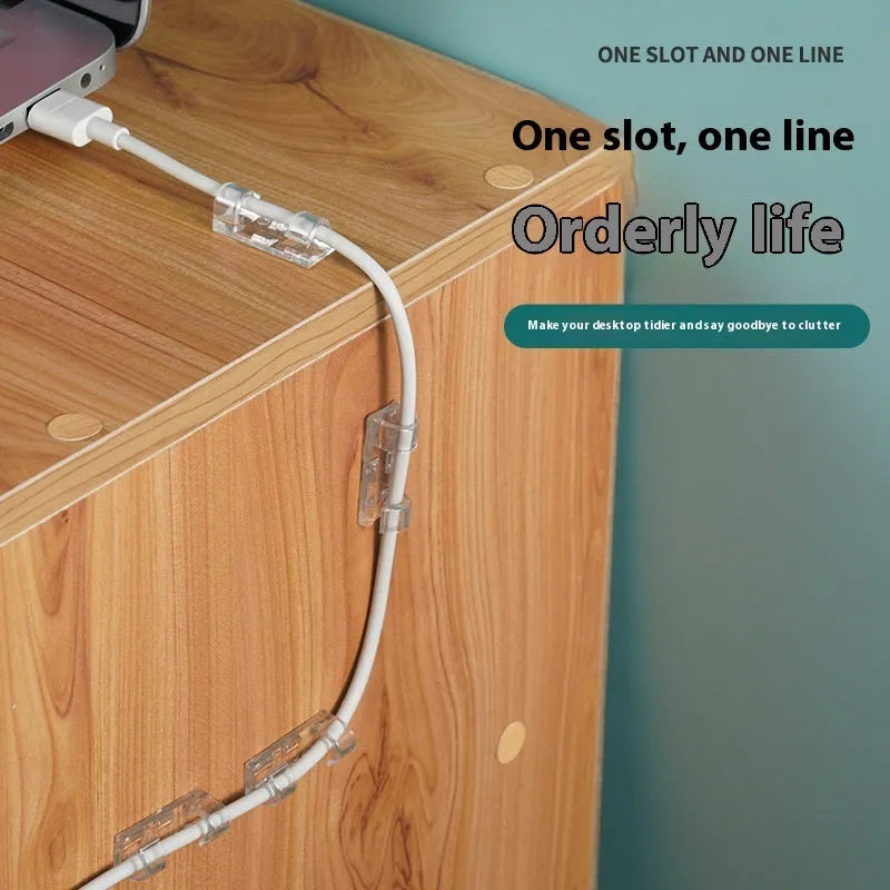 Transparent plastic self-adhesive cable clip holding a white wire against a wall.