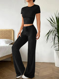 Black women's high waist trousers and short sleeve t-shirt co-ord set laid flat.