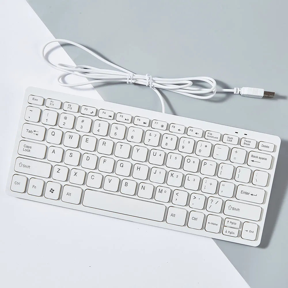 Compact USB wired mini keyboard in black, white, pink, or blue on a desk.