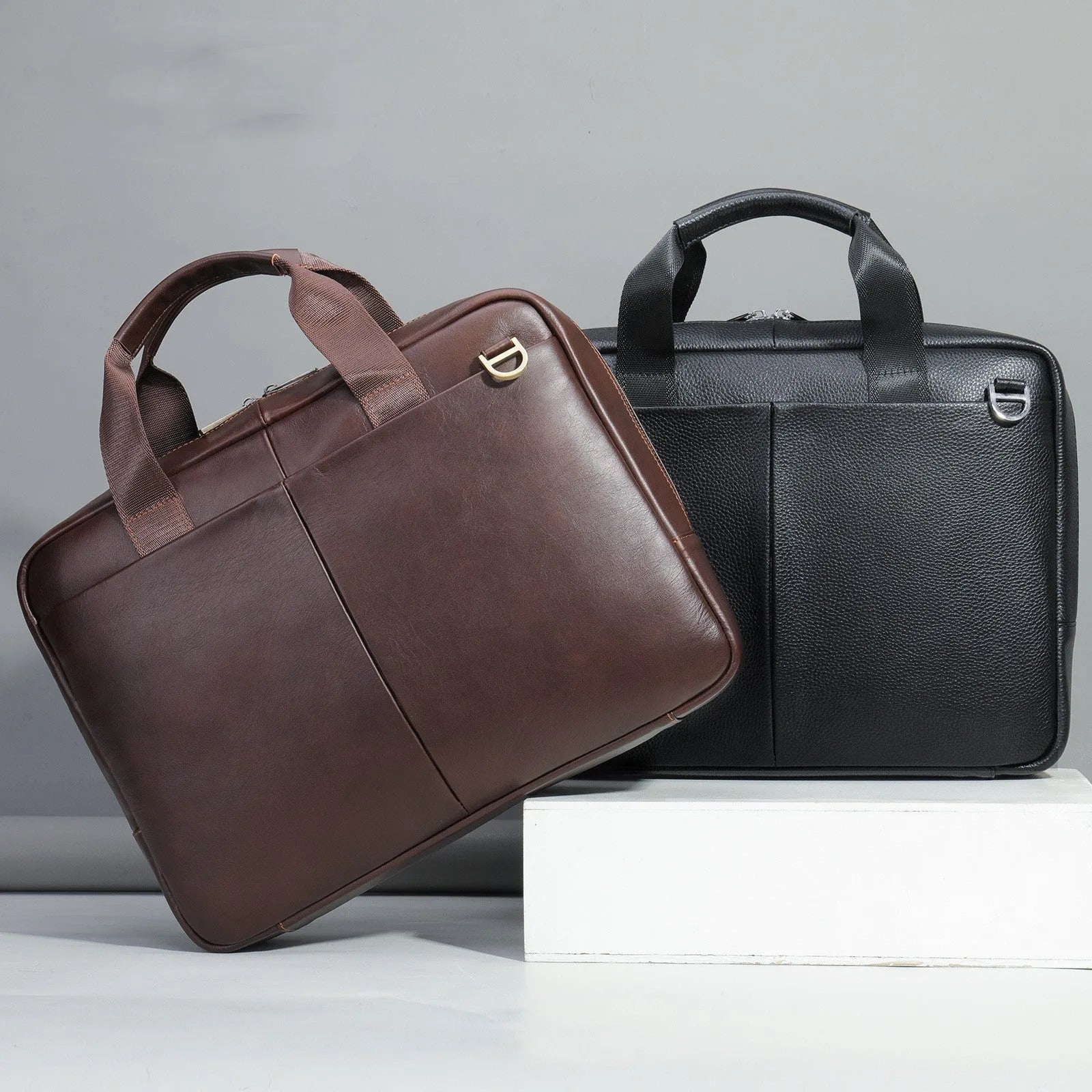 Black cowhide leather one shoulder computer handbag with sewing thread detail on a white background