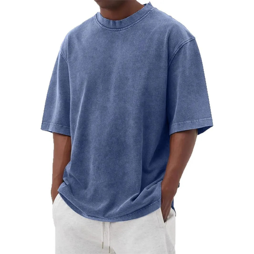 Man wearing a loose-fit, stone-washed grey t-shirt with a distressed solid colour finish and half sleeves.