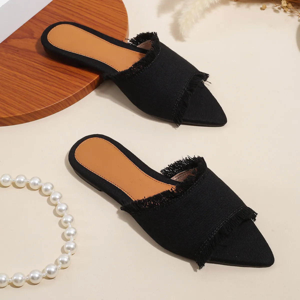Solid colour denim women's slippers with a tassel detail, showing leather lining and PVC sole.