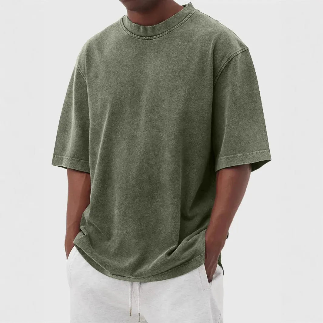 Man wearing a loose-fit, stone-washed grey t-shirt with a distressed solid colour finish and half sleeves.