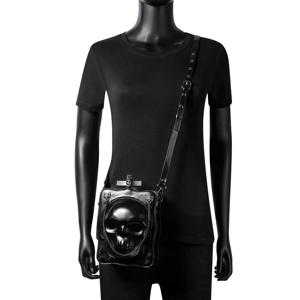Black mini square messenger bag with embossed skull design, featuring stitching, rivets, chain details and zipper closure