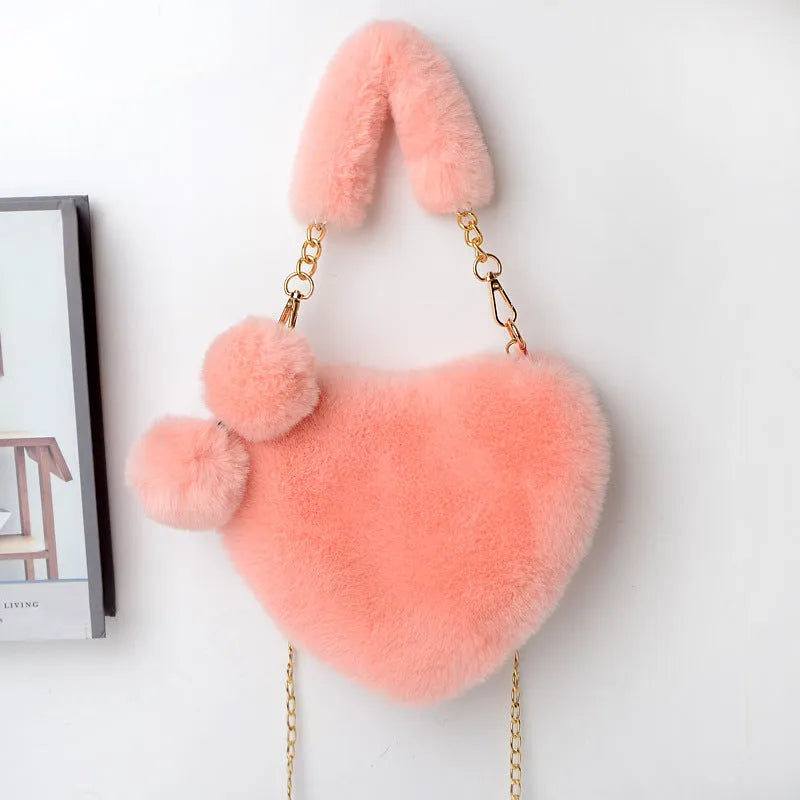 A soft, heart-shaped plush handbag for women in a medium size with a detachable shoulder strap.