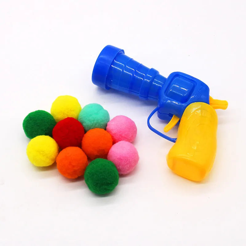Pet toy launcher gun and soft plush balls for interactive play with cats and dogs.