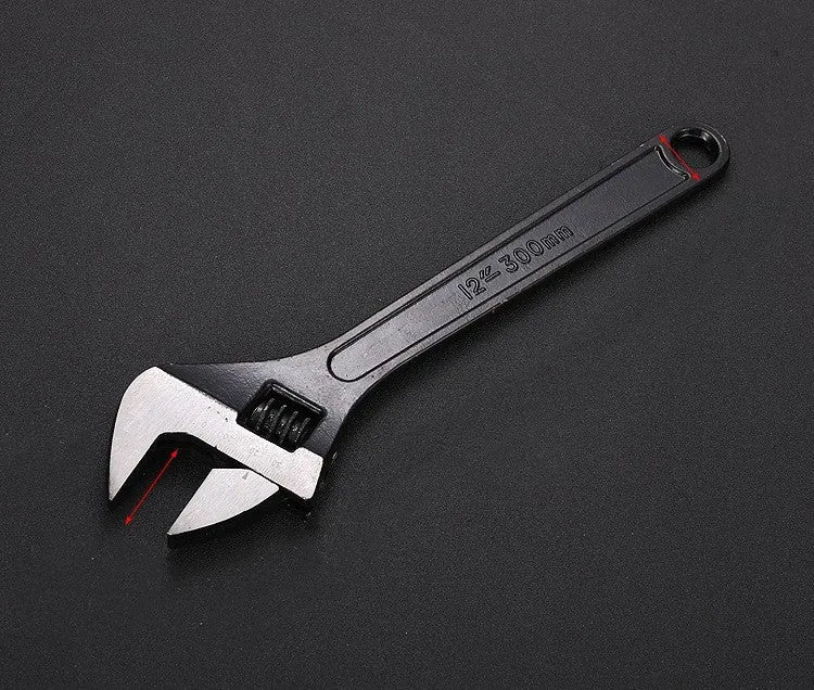 Blackened high-carbon steel adjustable open-end wrench with ergonomic handle on a workbench.