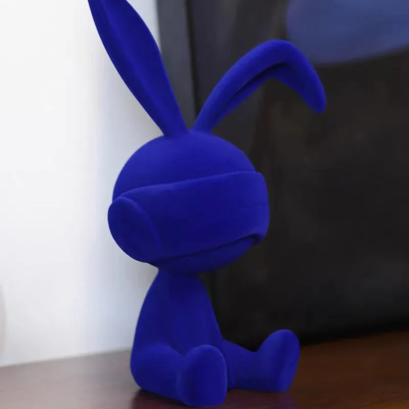 Suede blindfold rabbit resin table ornament in chosen colour on a wooden surface.