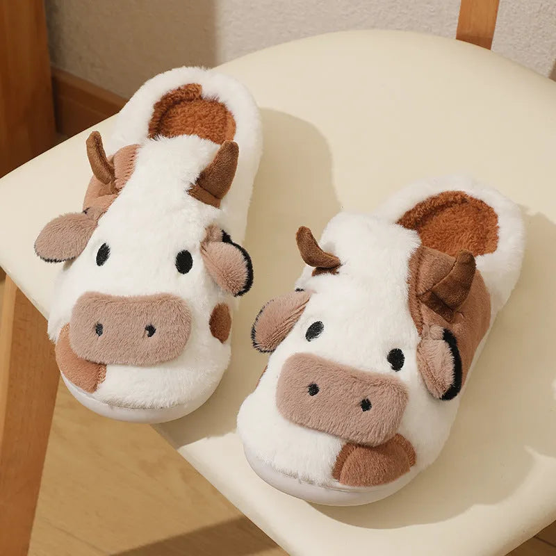 White cartoon cow plush house slippers for women with a non-slip textured sole.