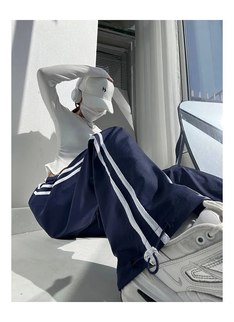 Navy blue loose straight-leg trousers with contrast ribbon trim and a slimming drape
