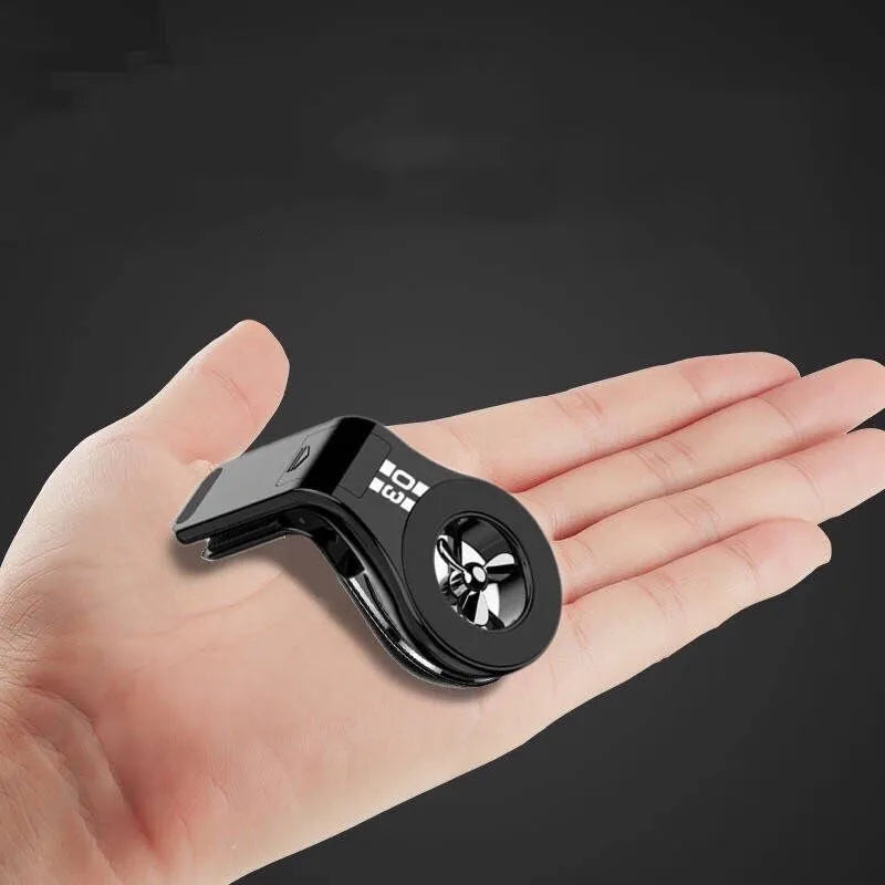 Black magnetic car phone holder clipped to a car air vent, showing adjustable paddle and fragrant slice.