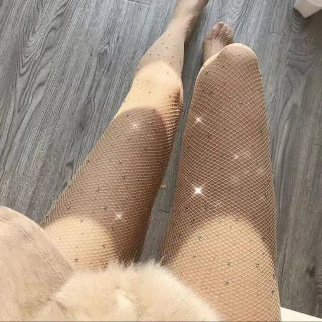 A pair of thin mesh fishnet stockings for women in solid skin colour, laid flat.