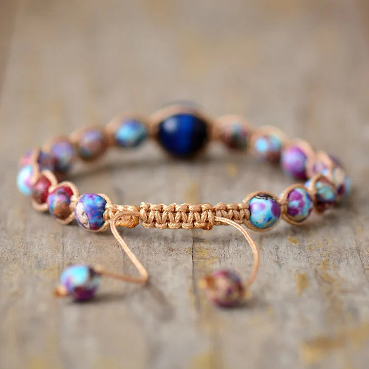 Hand woven friendship bracelet with adjustable cord and single Emperor Stone bead on a plain background.