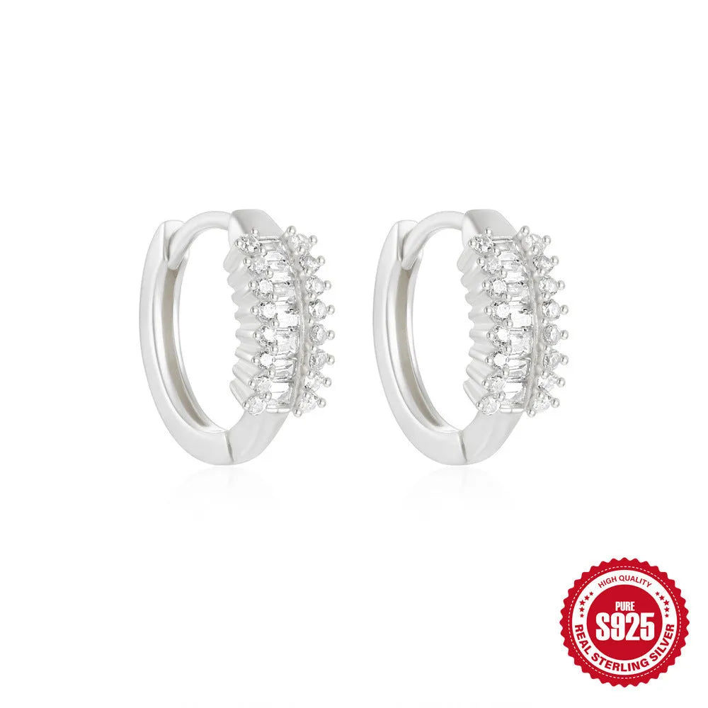 A pair of small, round, geometric stud earrings made of sterling silver with an electroplated finish.