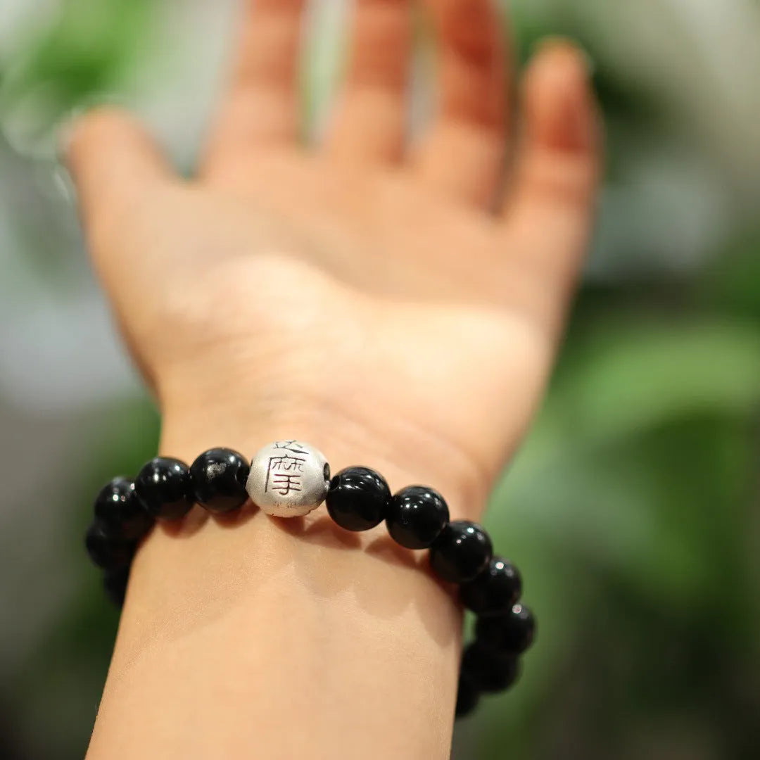 Close-up of a women's bracelet with spherical black agate beads and a shiny sterling silver clasp on a wrist.