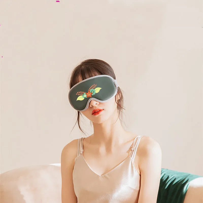 Green portable eye steam massage goggles with USB cable on a table.