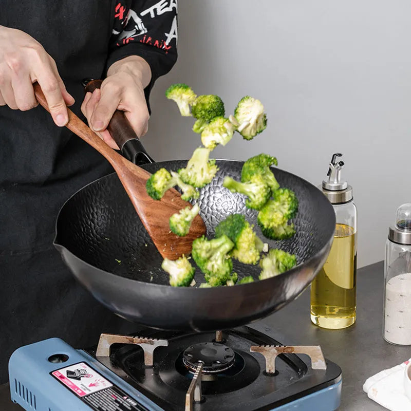 Traditional handmade iron wok pan with wooden handle and induction-compatible base