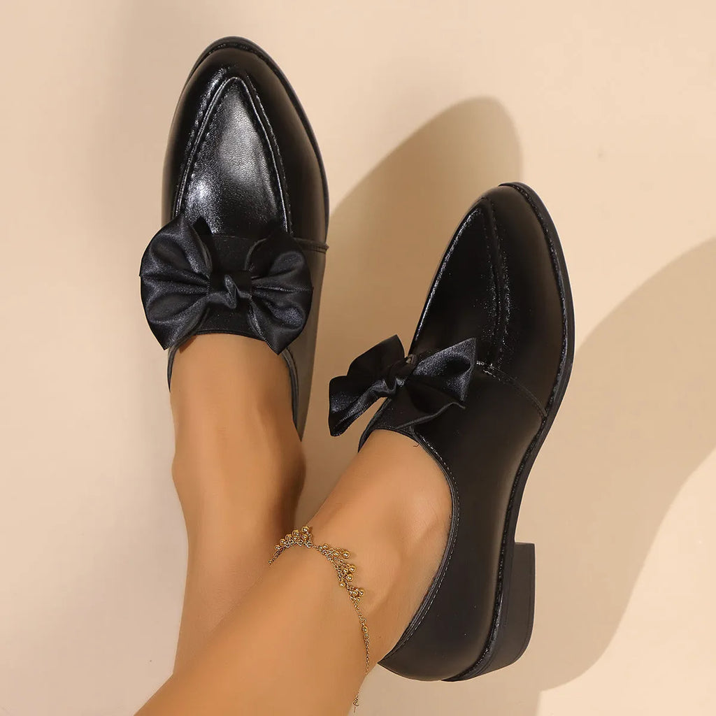 Women's British-style leather-look shoes with decorative bow detail on pointed toe