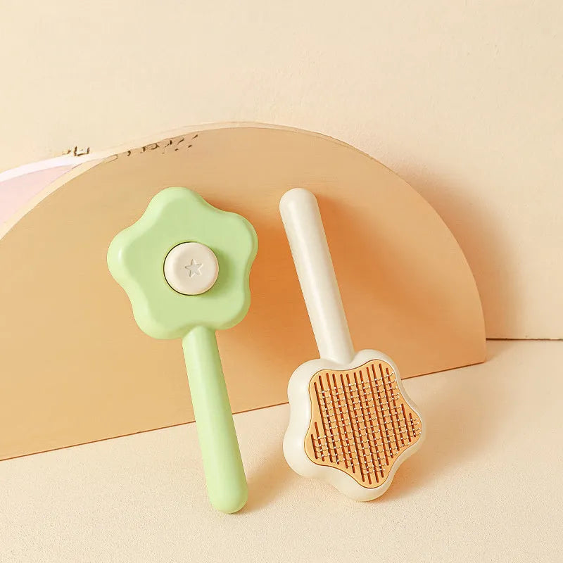 Green and yellow self-cleaning cat grooming comb with stainless steel needles on a white background.