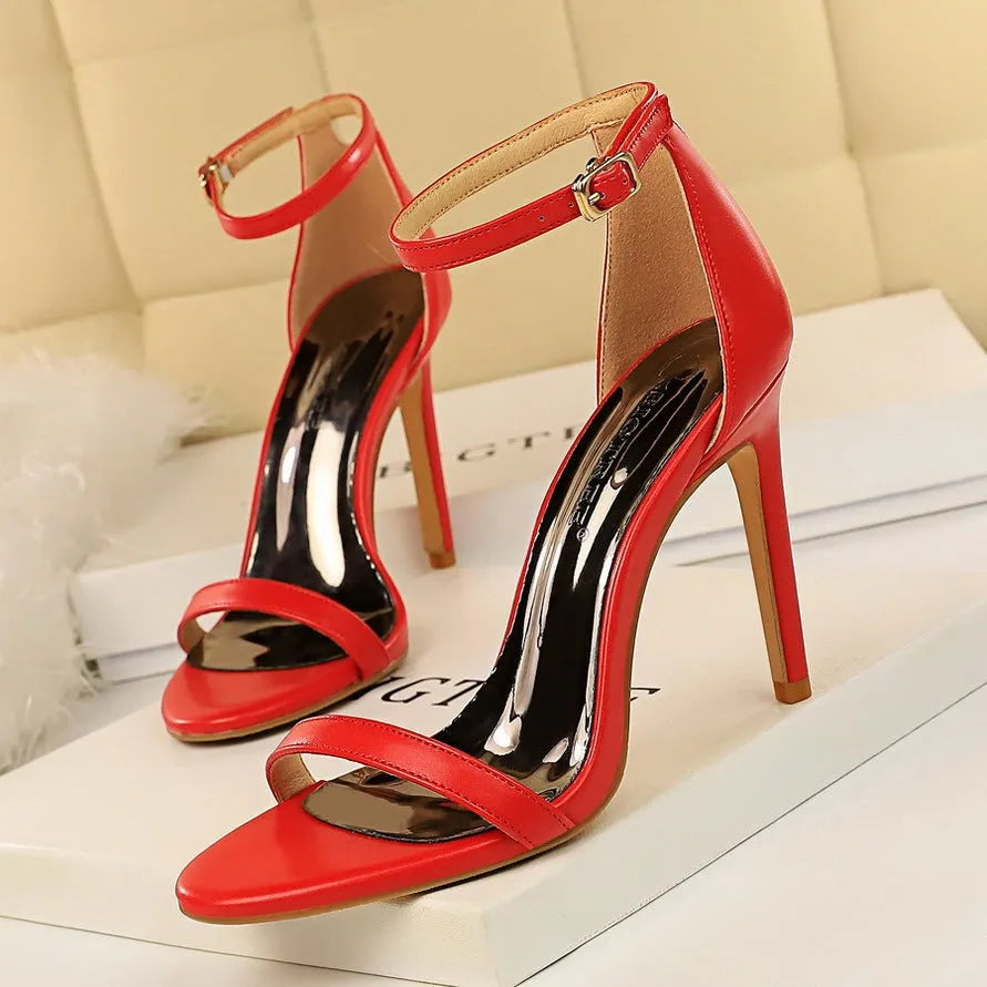 Women's ankle-strap high heel sandals in an open-toe design, showing buckle detail and available in multiple colours.