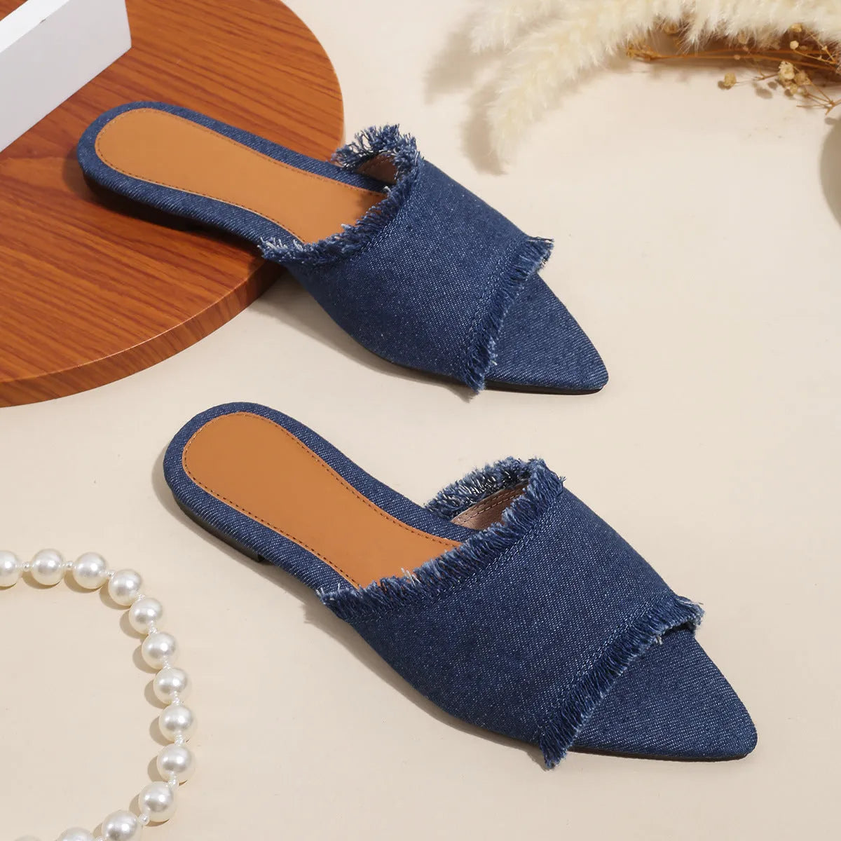 Solid colour denim women's slippers with a tassel detail, showing leather lining and PVC sole.