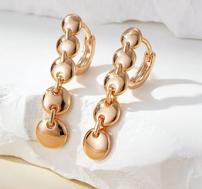 A pair of long, round, gold-toned retro earrings with a woven copper design.