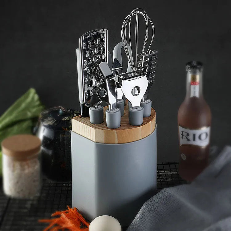 Stainless steel kitchen gadget set with whisk, grater, peeler, fruit knife, scissors, and tray lifter in grey