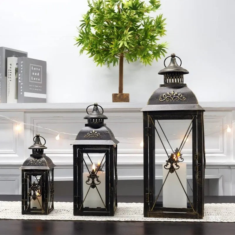 Black wrought iron floor lantern with glass panels on a stone patio.