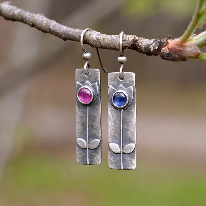 Pair of women's antique finish earrings with red sapphires, geometric shape, and ellipse design on a retro electroplated metal setting.