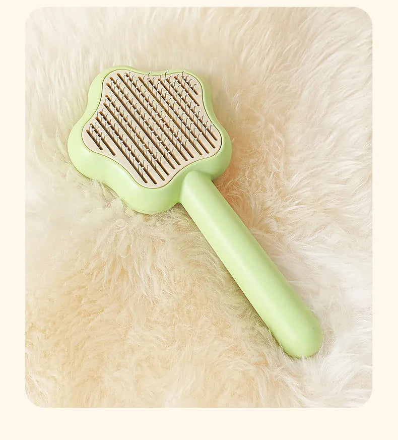 Green and yellow self-cleaning cat grooming comb with stainless steel needles on a white background.