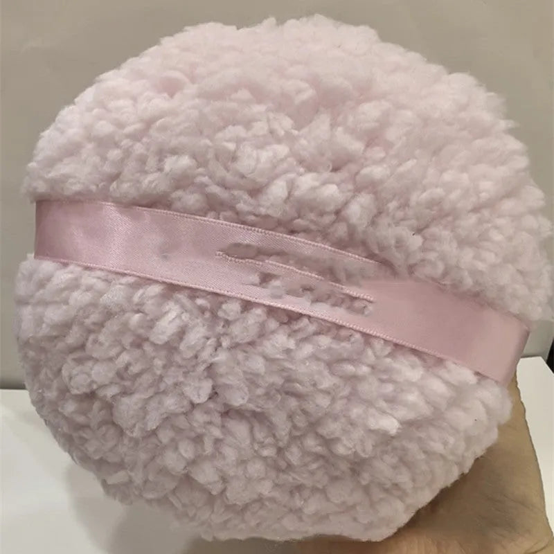 Oversized rectangular plush powder puff in white on a pink background.