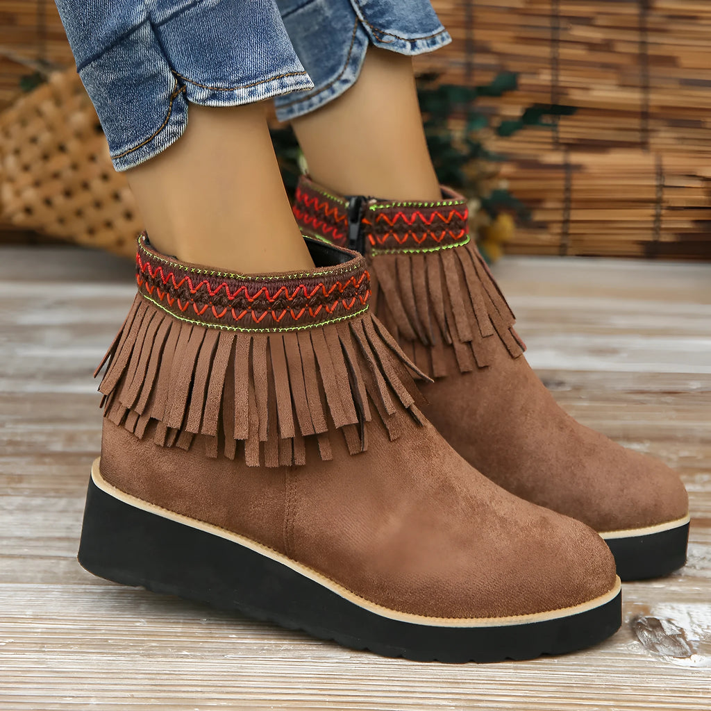 Women's black suede wedge ankle boot with side zip and tassel detail on a thick rubber platform sole.