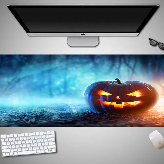 Oversized black Halloween-themed mouse pad with spooky artwork on a desk next to a gaming mouse.