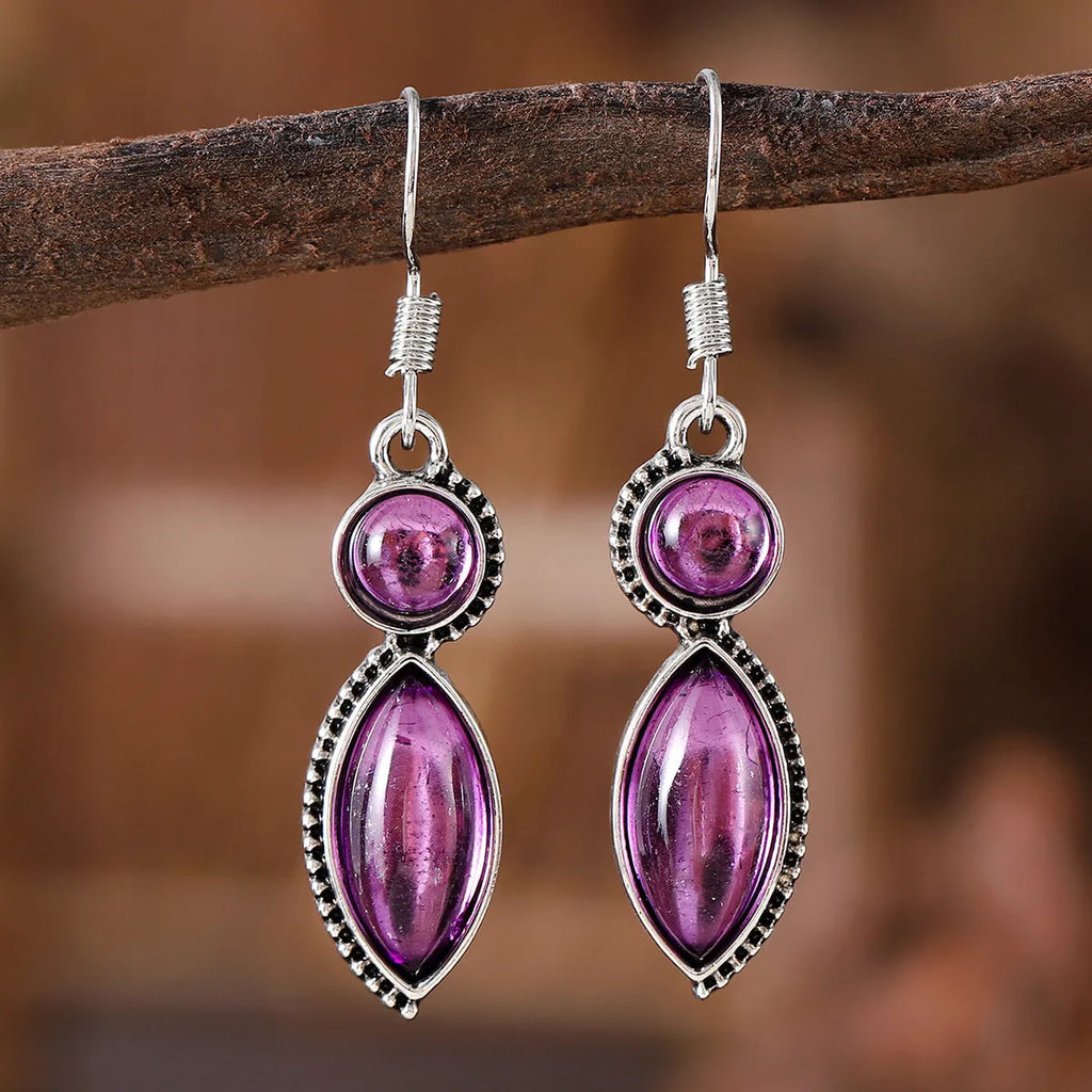 A pair of geometric vintage earrings with a black and purple electroplated finish, showing a pendant design with round elements.