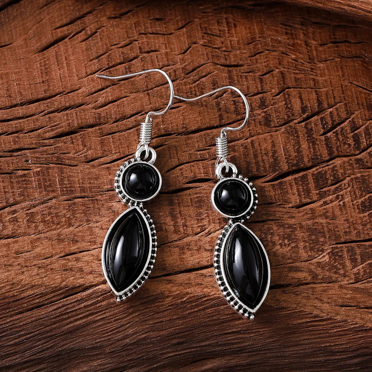 A pair of geometric vintage earrings with a black and purple electroplated finish, showing a pendant design with round elements.