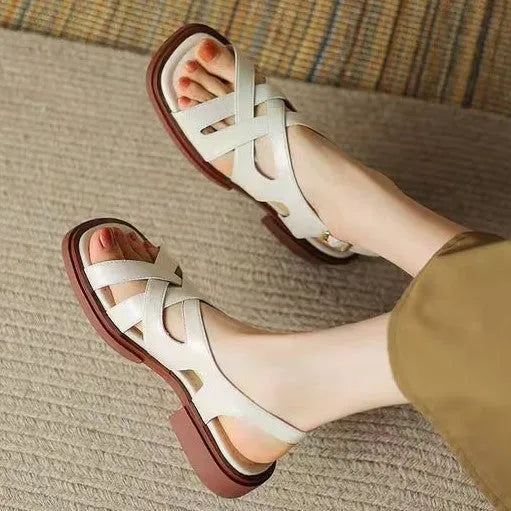 Glossy black patent leather women's sandals with a cross-band design, square toe, and low rubber sole.