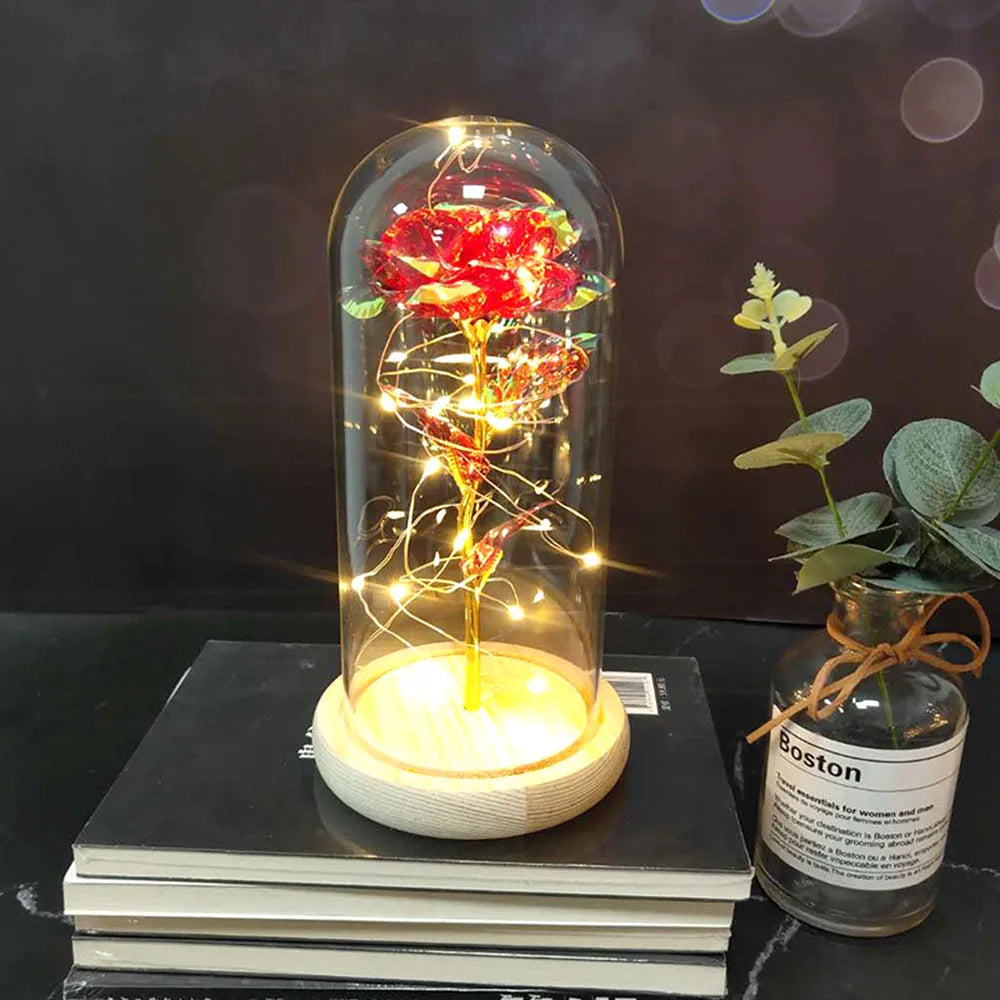 Simulated pink silk rose inside a glass dome with glowing LED fairy lights